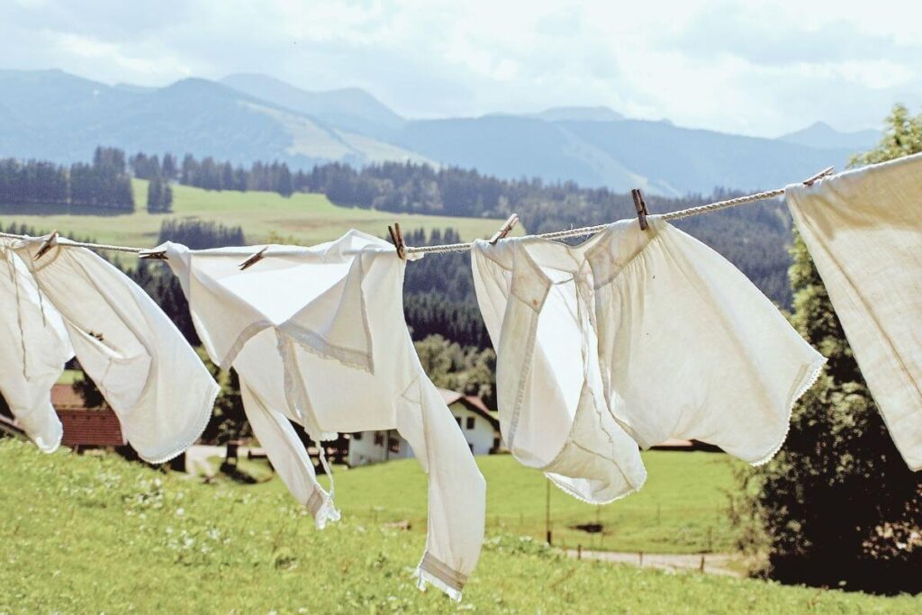 Organic white garments drying on a clothesline in a rural landscape, representing sustainable fabric alternatives