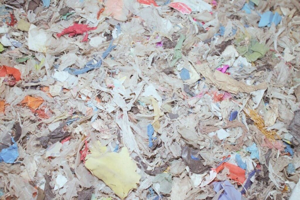 Piles of shredded mixed textile waste showing the challenges of recycling synthetic fabrics